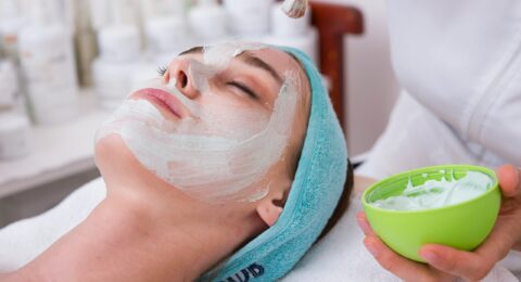 woman lying on blue towel with white cream on face